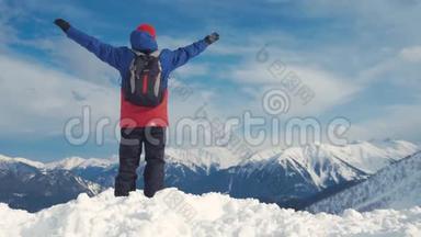 男子背着背包<strong>站在</strong>雪<strong>山顶</strong>上，胜利者摆姿势，举起双手欣赏风景和成就